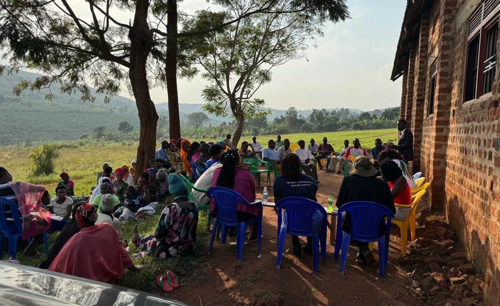 Group of people sitting on grass and plastic chairs outside next to an african church in Uganda