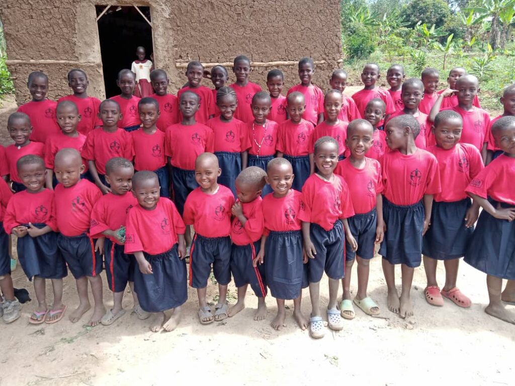 Group of children in uniform smiling and standing outside the Okoa Refuge center